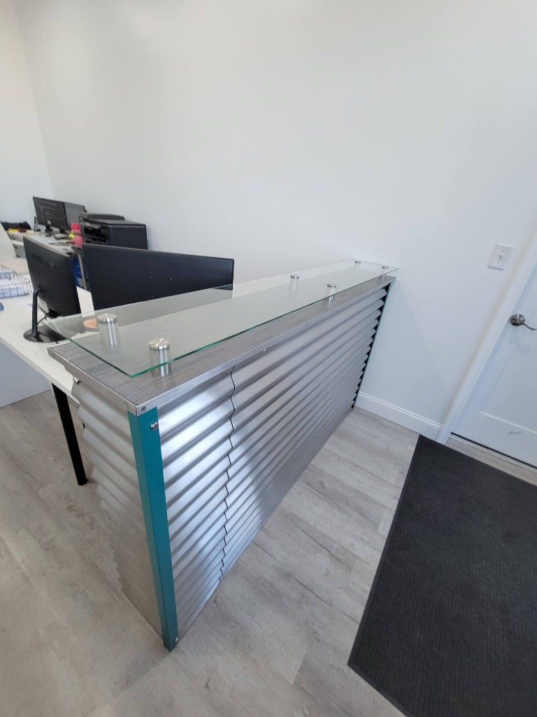 Custom metal reception counter with glass top and corrugated aluminum panels