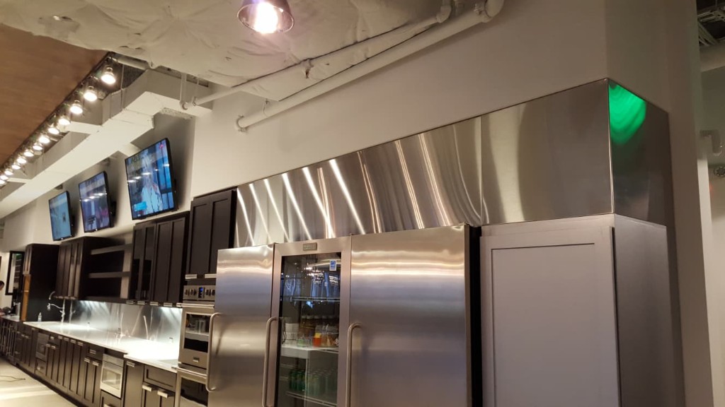 Commercial stainless steel hood and wall cladding in a food-service kitchen