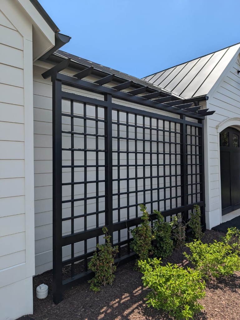 Custom black metal trellis and pergola on a residential home